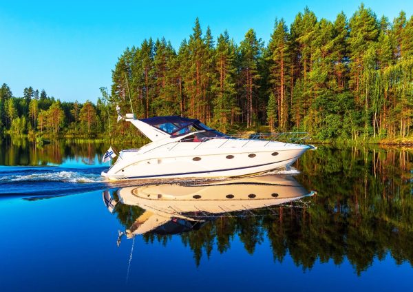 Moottorivene Suomen lipulla metsäisen rannan edustalla